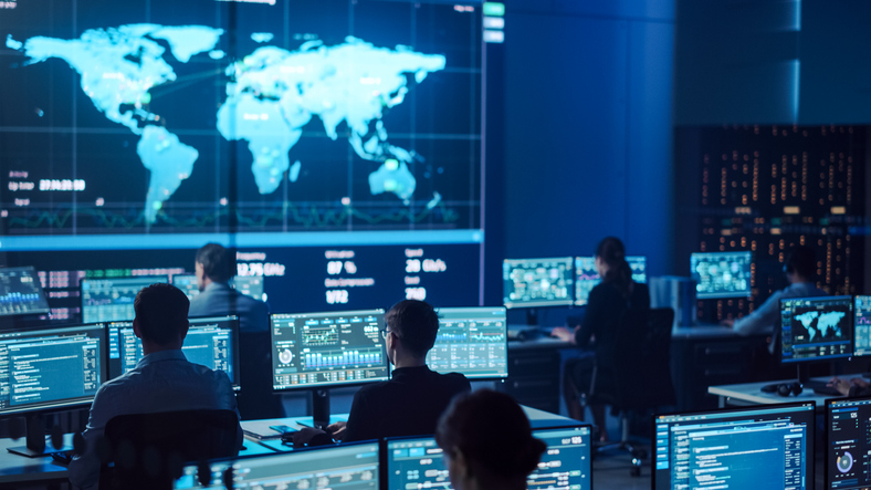 Team of Professional Computer Data Science Engineers Work on Desktops with Screens Showing Charts, Graphs, Infographics, Technical Neural Network Data and Statistics. Dark Control and Monitoring Room.